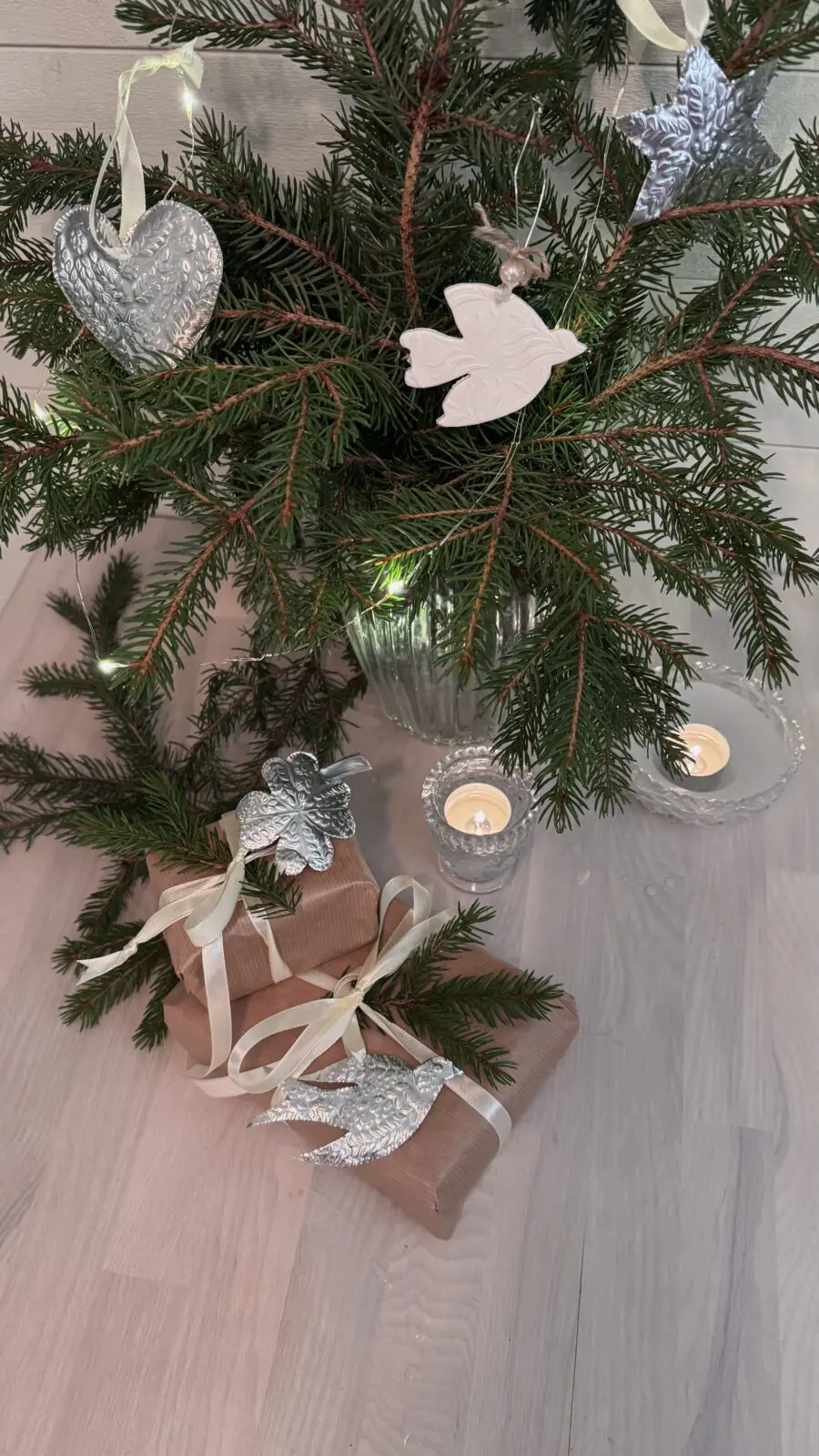 Granris i vas dekorerat med handgjorda julhängen i vit fimolera och silvermetall, tillsammans med paket pyntade med samma hängen – julpyssel från CC Hobby.