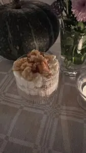 Närbild på krämig äppelcheesecake i glas med smuldeg på toppen.