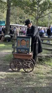 En positivspelare i tidstypiska kläder spelar på en vackert dekorerad vevorgel under Skansens höstmarknad
