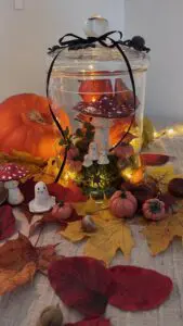DIY höstpyssel i glasburk med små lerfigurer – flugsvamp, pumpor och spöken dekorerade med mossa, höstlöv och ljusslinga. Ett enkelt halloweenpyssel för vuxna och barn.