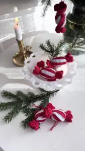 Närbild på virkade julkarameller i rött och vitt i vit skål – enkelt julpyssel