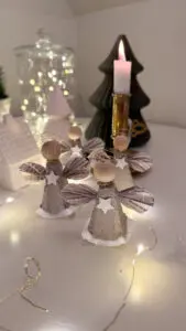 Änglar av äggkartong med pappersvingar och glitterstjärnor på bord